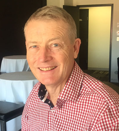 Man with short grey hair wearing red and white checked shirt